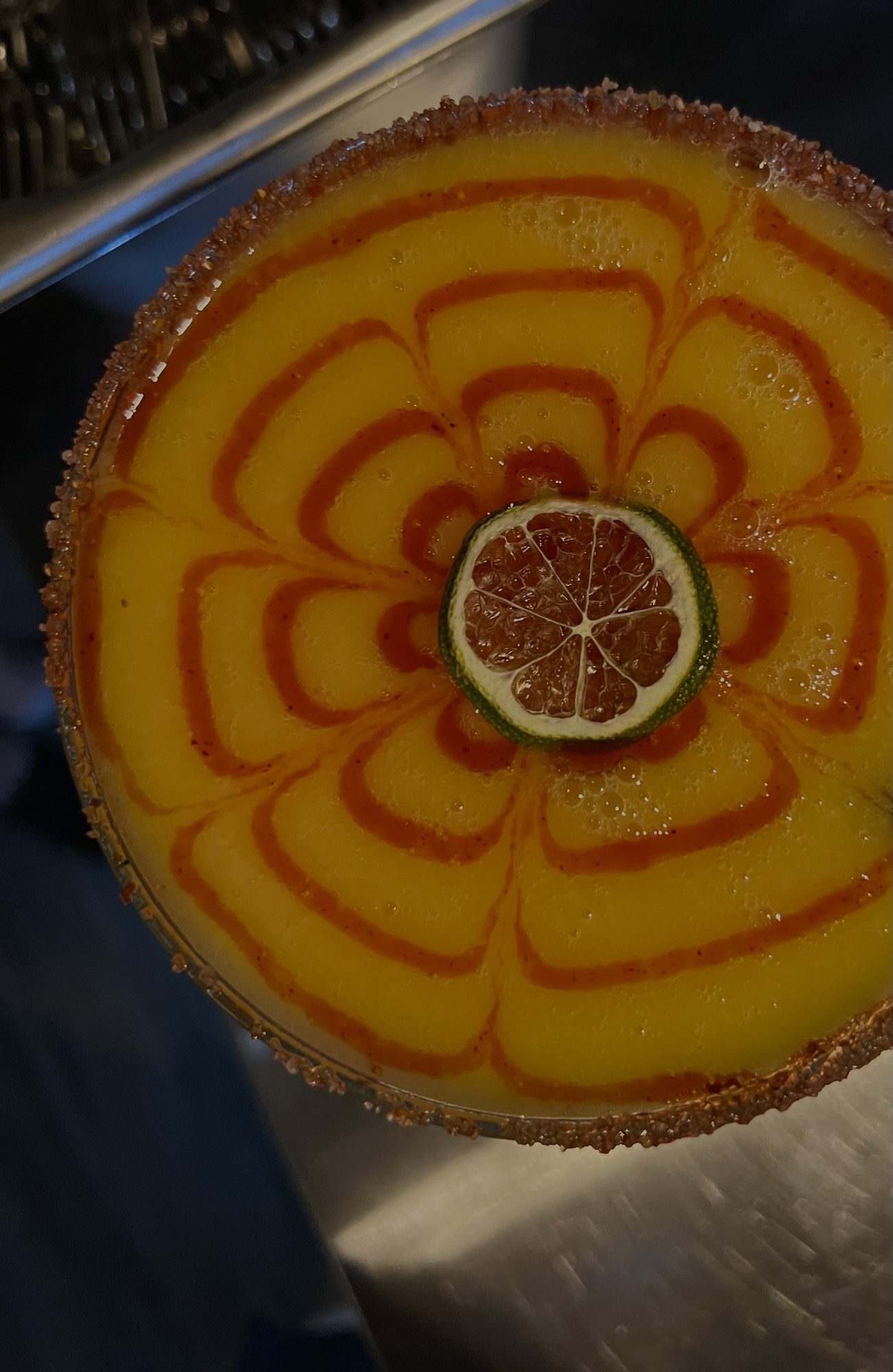 An amber cocktail garnished with a dehydrated orange wheel and a dusted rim