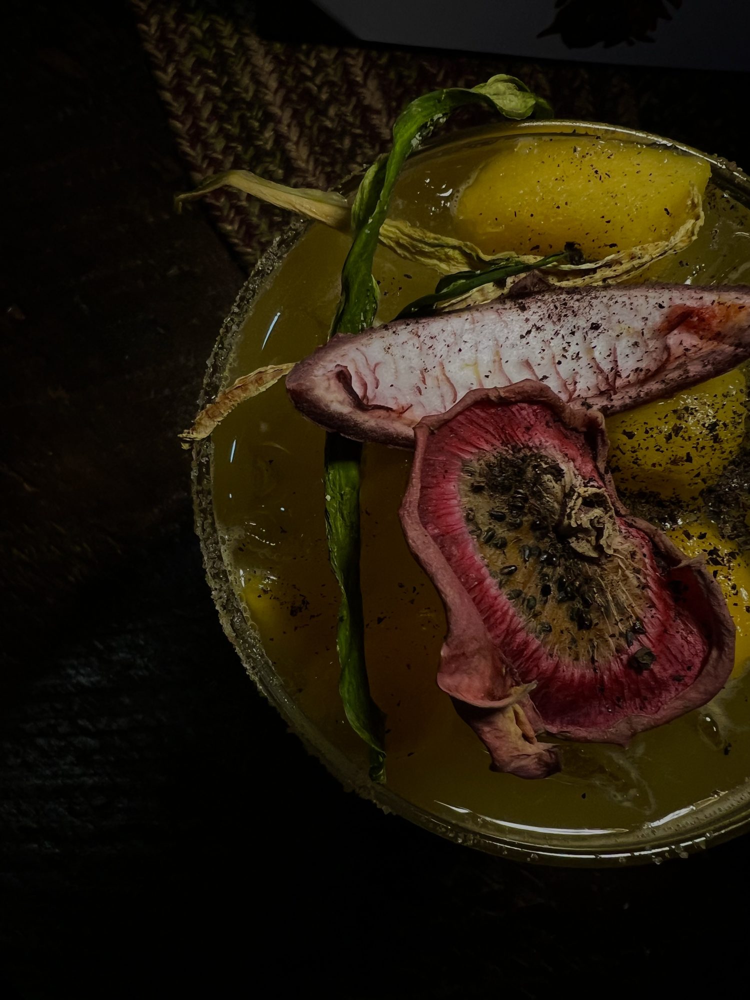 A smoked cocktail in a cut-glass tumbler with lime, against a black backdrop