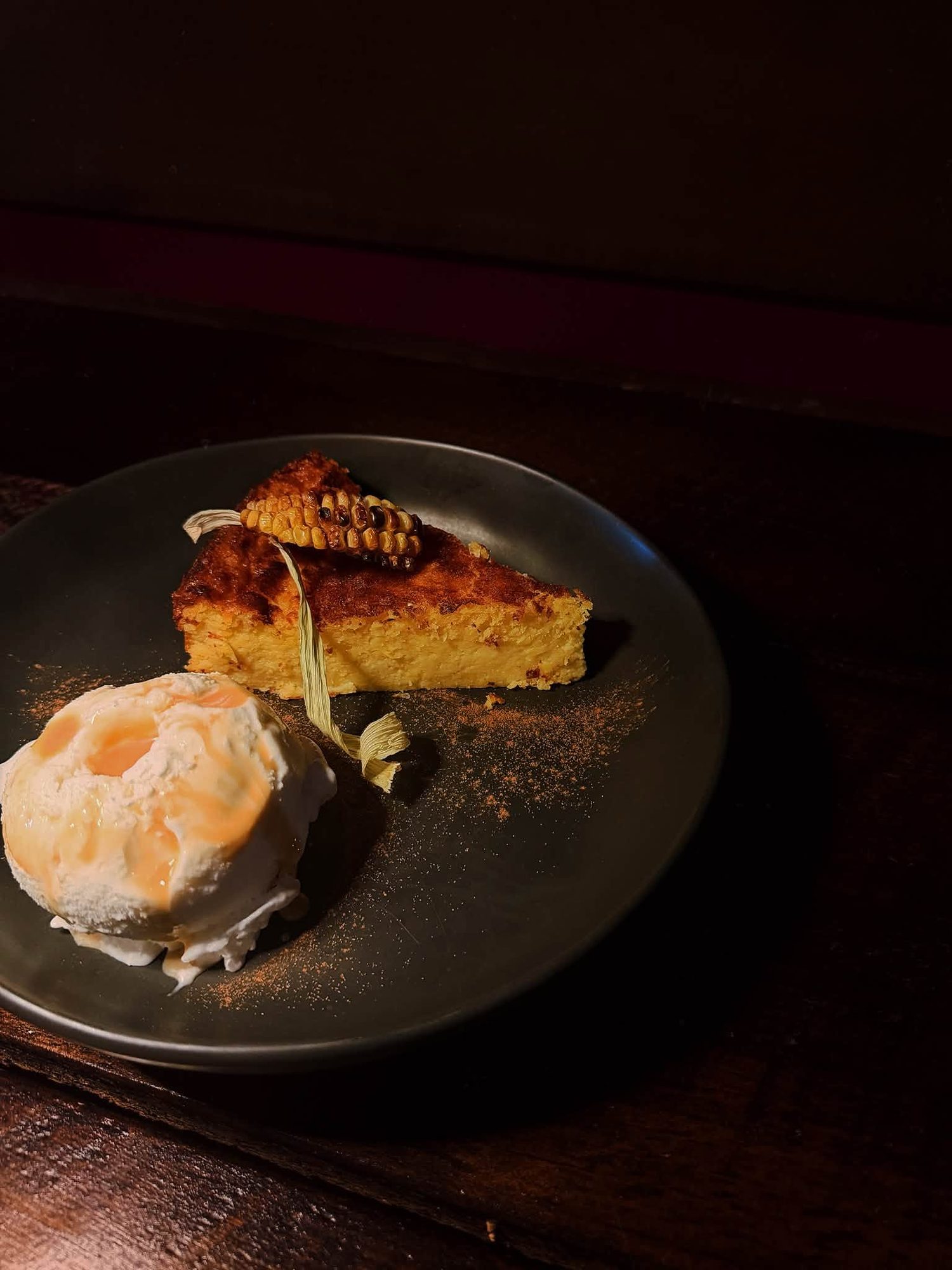 A plated dessert with cream, presented on black ceramic