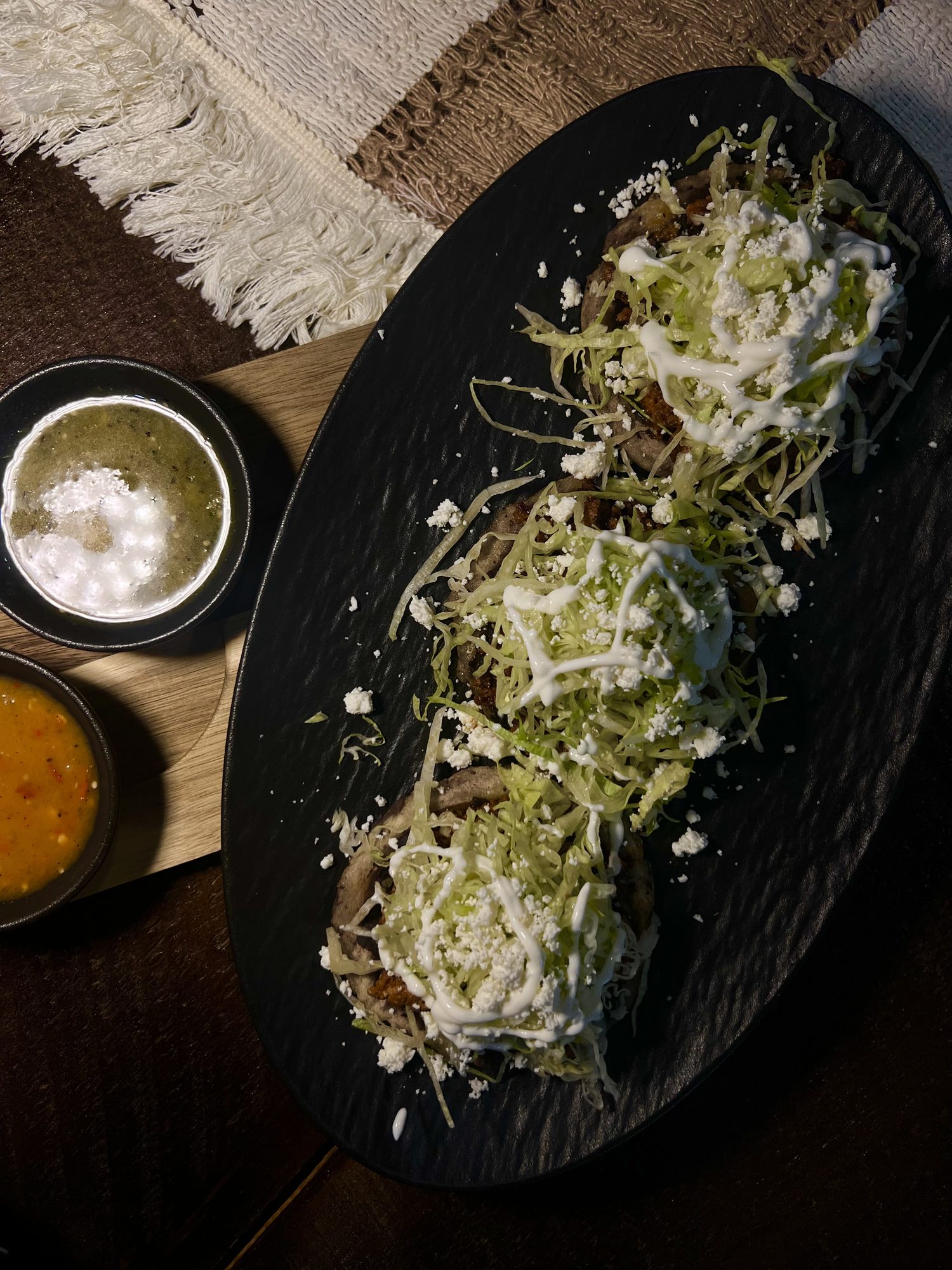 Enchiladas verdes on black ceramic, finished with cream and crumbled cheese