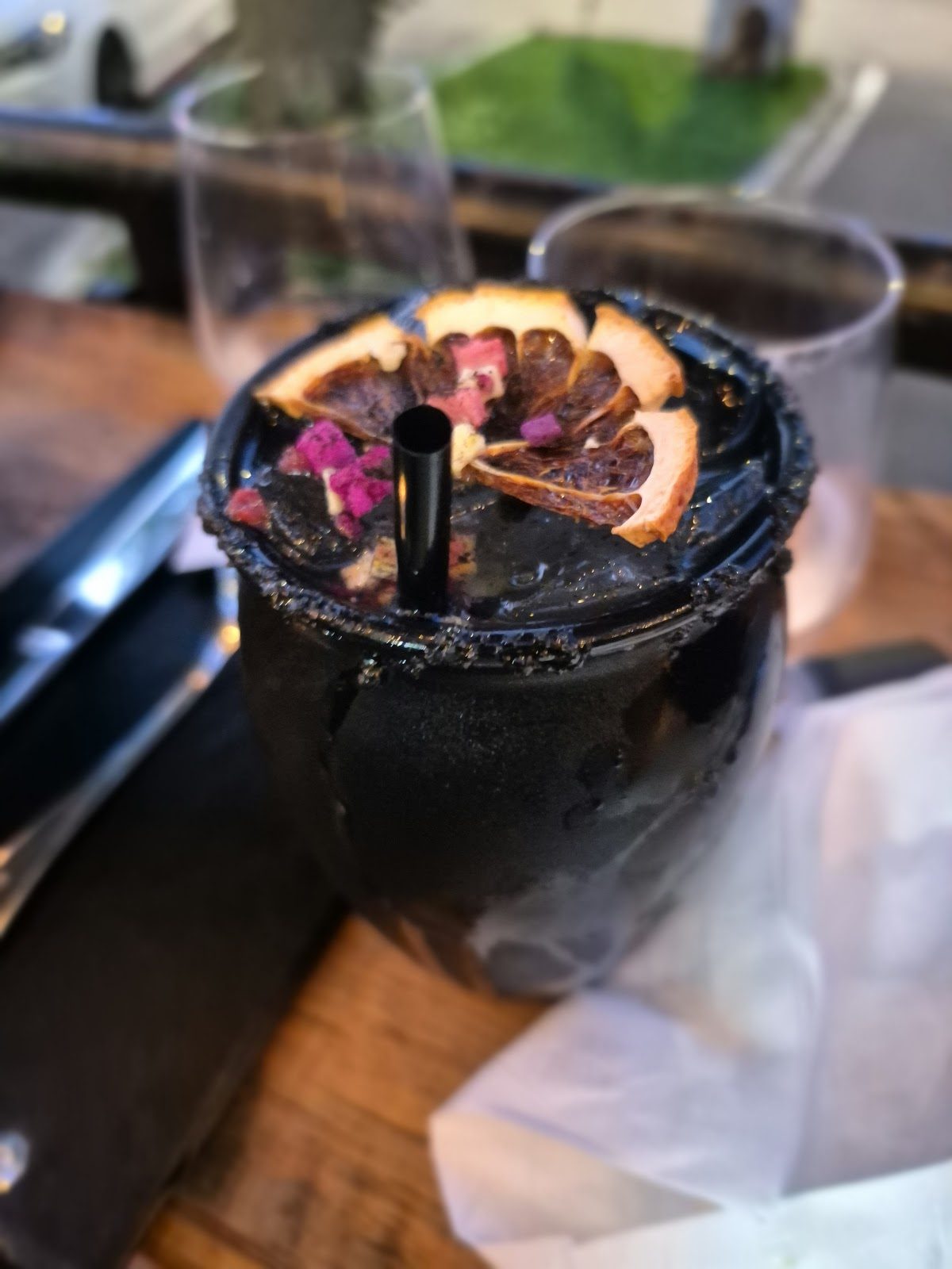 A margarita with a dehydrated orange wheel and dark dressed rim