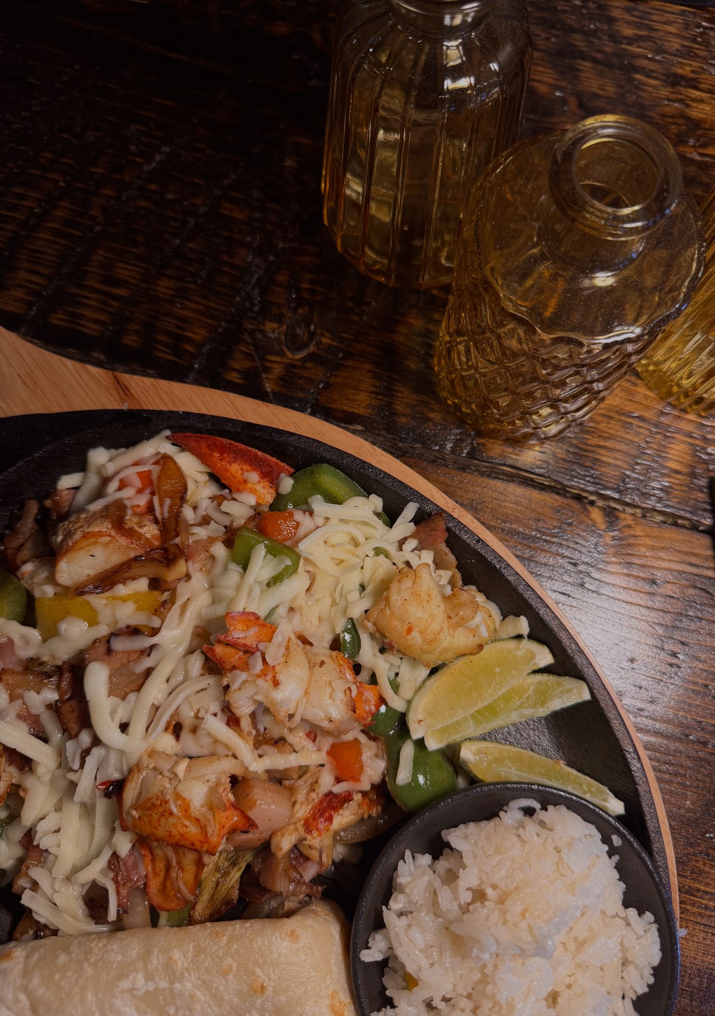 A shared platter with quesadillas, rice and salsas on a dark wood table